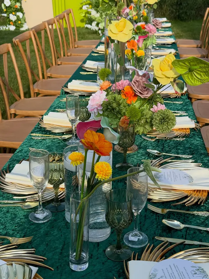 Outdoor dinner table with green linens and gold chairs