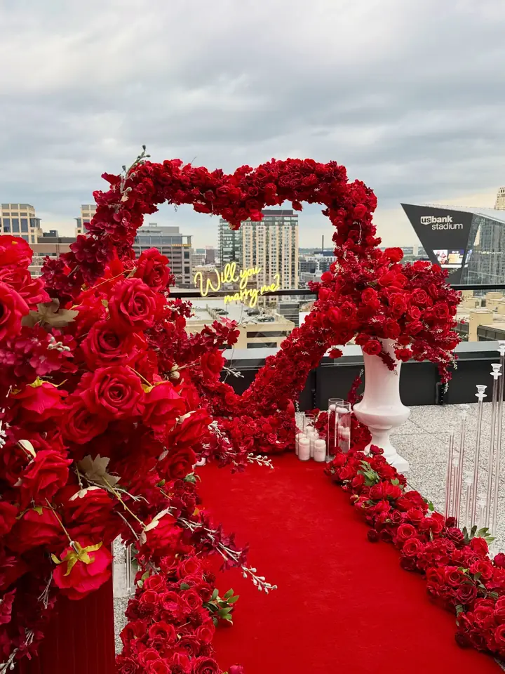 Red rose heart arch and red carpet proposal setup on a Minneapolis rooftop