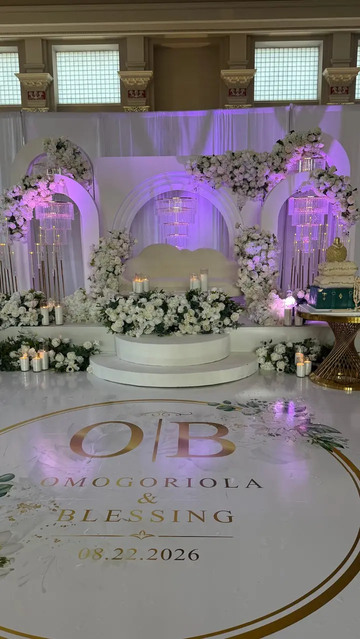 Wedding reception stage with white florals and a custom monogram floor at the Minneapolis Grain Exchange